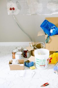 Various painting tools and cans of paint scattered on the floor. Essentials for a DIY painting project.