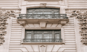 Elegant building facade in soft beige with ornate balconies and floral carvings